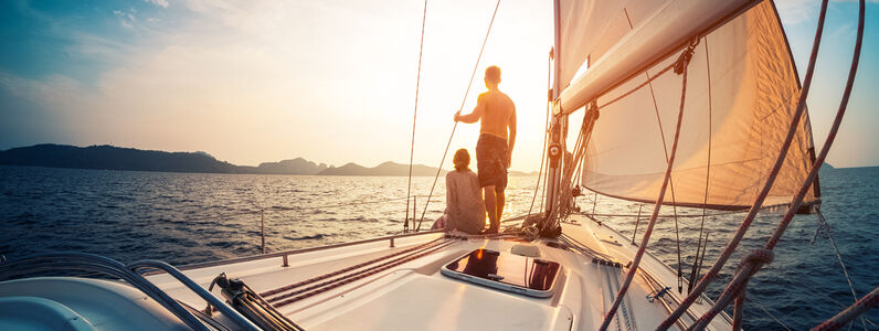 Couple,Enjoying,Sunset,From,The,Deck,Of,The,Sailing,Boat
