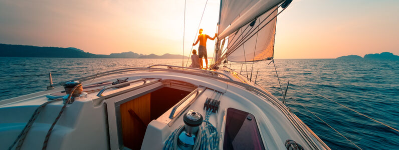 Young,Couple,Enjoys,Sailing,In,The,Tropical,Sea,At,Sunset