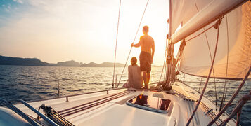 Couple,Enjoying,Sunset,From,The,Deck,Of,The,Sailing,Boat